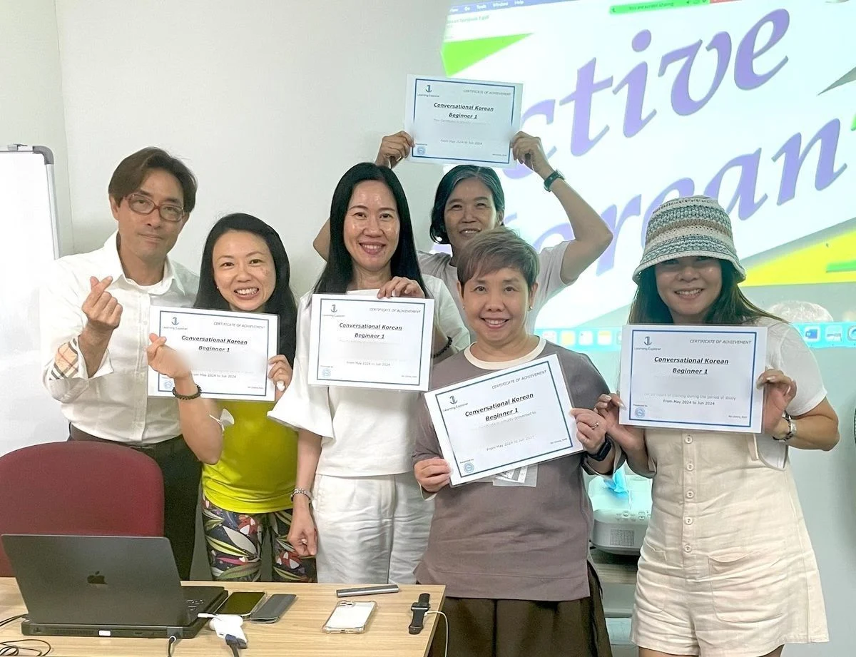 A beginner class holding up their certificates with their teacher