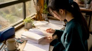 Young woman studying Korean language books at desk
