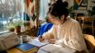 Young woman studying Korean with notes and audio