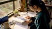 Young woman studying Korean language books at desk