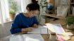 Young woman writing Korean syllable blocks at table