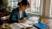 Woman writing Hangul characters at desk